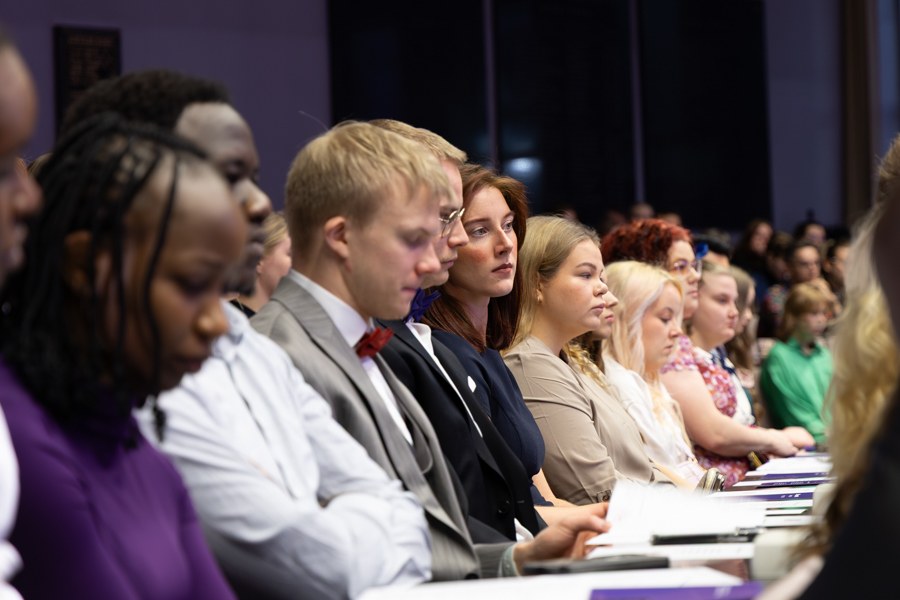 Valmistuneita opiskelijoita istuu TAMKin juhlasalin katsomossa ja seuraa juhlaohjelmaa.