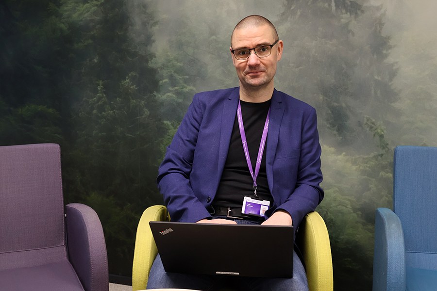 Puvun takkiin pukeutunut mies opettaa luokassa. 