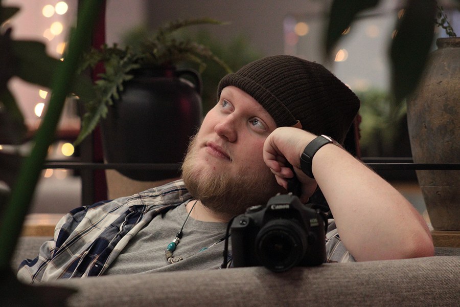 Nuori mies lakki päässä istuu tuolissa ja katsoo kaukaisuuteen. 