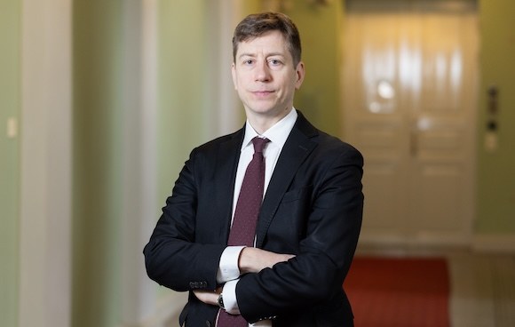 Tummaan pukuun pukeutunut mies.