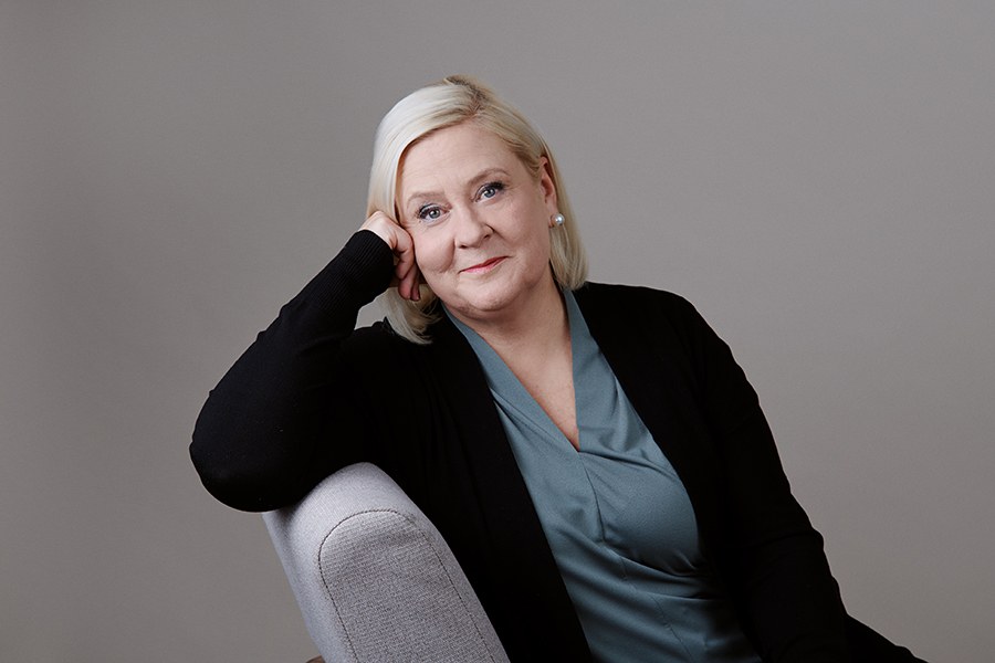 Nainen istuu tuolilla selkänojaan nojaten. 