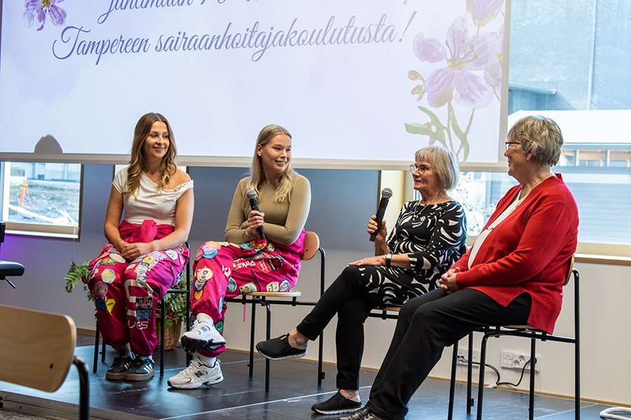Kaksi nuorta sairaanhoitajaopiskelijaa sekä kaksi iäkkäämpää sairaanhoitajaa istuvat tuoleilla paneelikeskustelussa.