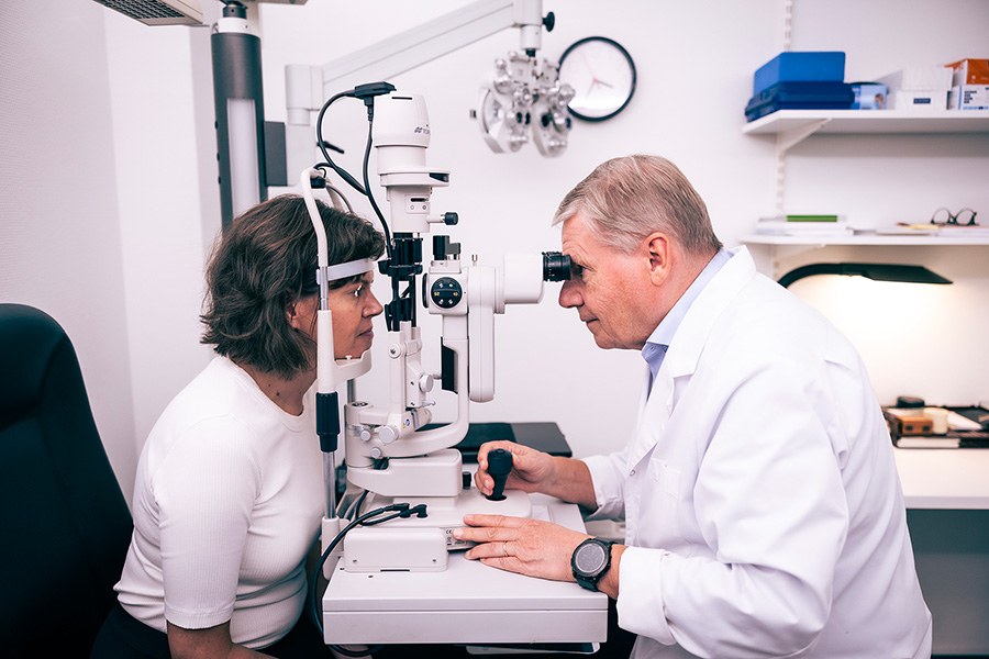 Hannu Uusitalo examining a patient's eyes with a slit-lamp microscope.