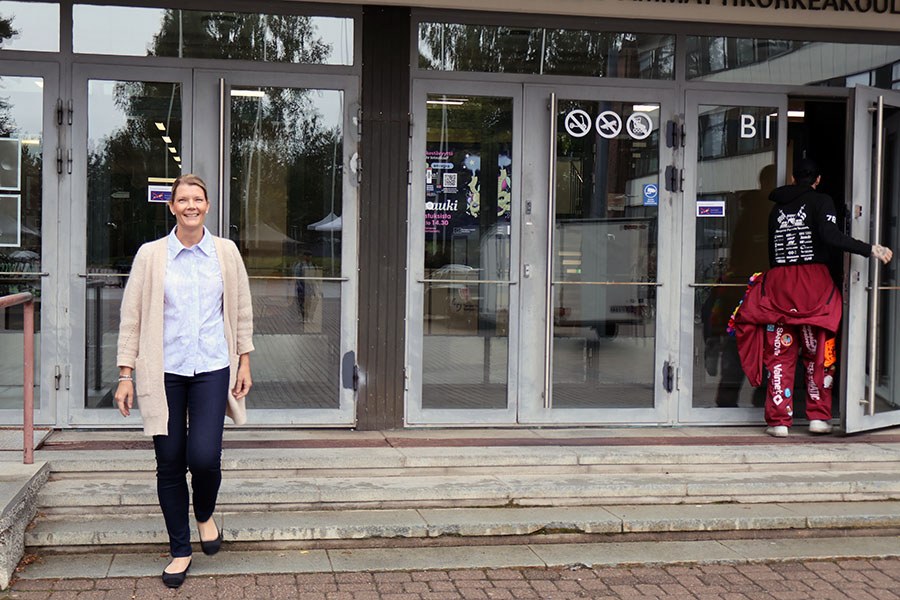 Nainen kävelee ulos korkeakoulun ovista.