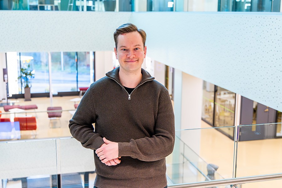 Lauri Ryyppö is leaning against a glass railing in a spacious lobby.