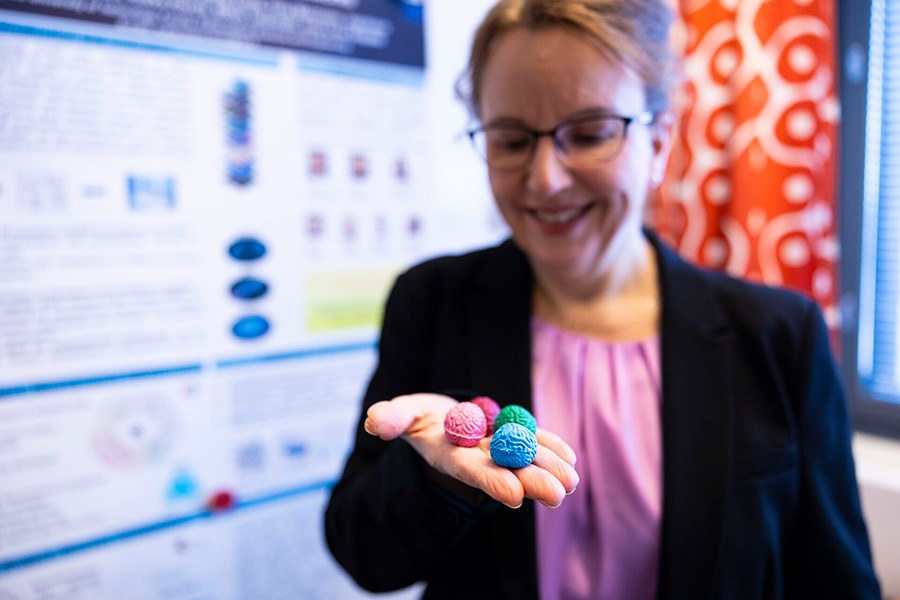 Marja-Leena Linne is holding a variety of mini-sized artificial brains on her palm.