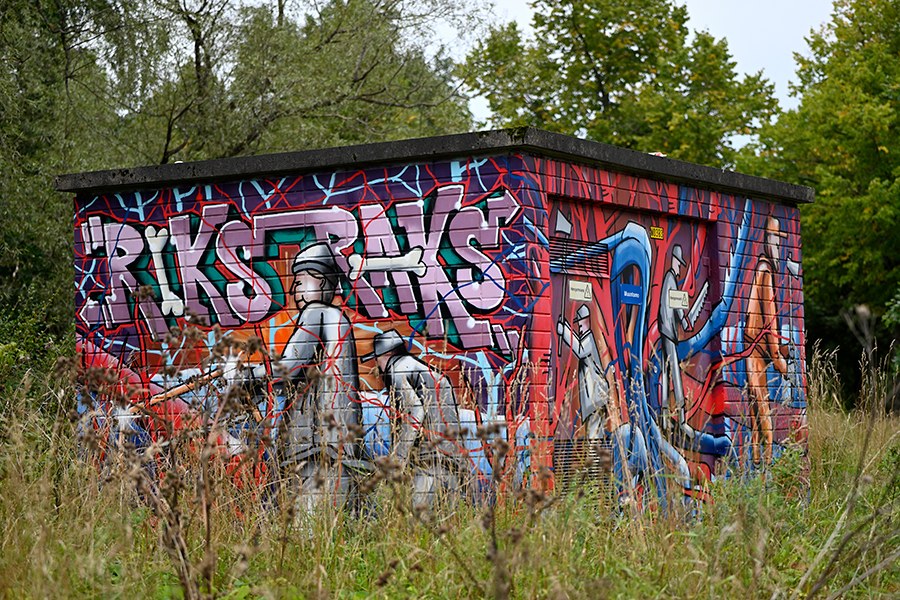 Värikäs graffitein maalattu rakennelma, ympärillä luontoa.