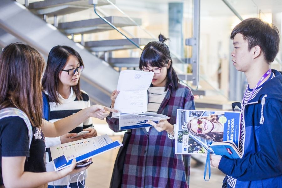 Asian students reading brochures of Tampere Universities.